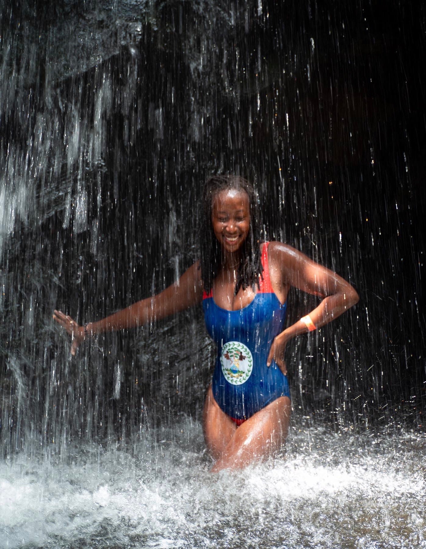 Front view of women's one-piece swimsuit inspired by the Belize flag, captured at Mayan King Waterfalls in Placencia, Belize.